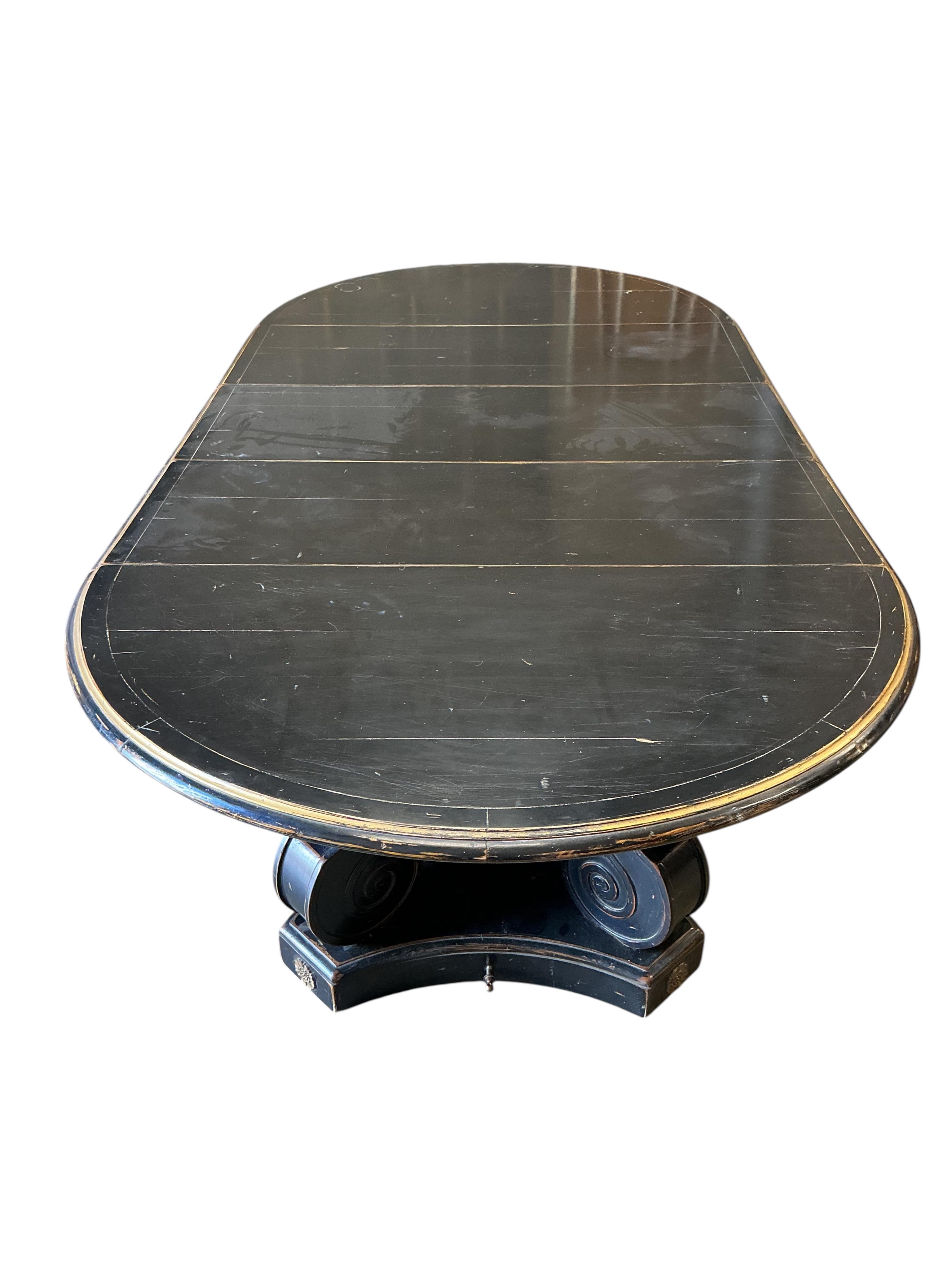 A Regency style ebonised, parcel gilt extending dining table, purchased from Liberty, diameter 150cm, 305cm extended three spare leaves, height